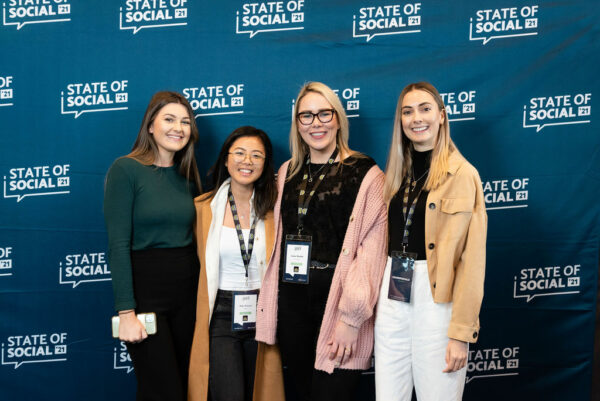Four delegates pose in front of the State of Social backdrop, State of Social ‘21